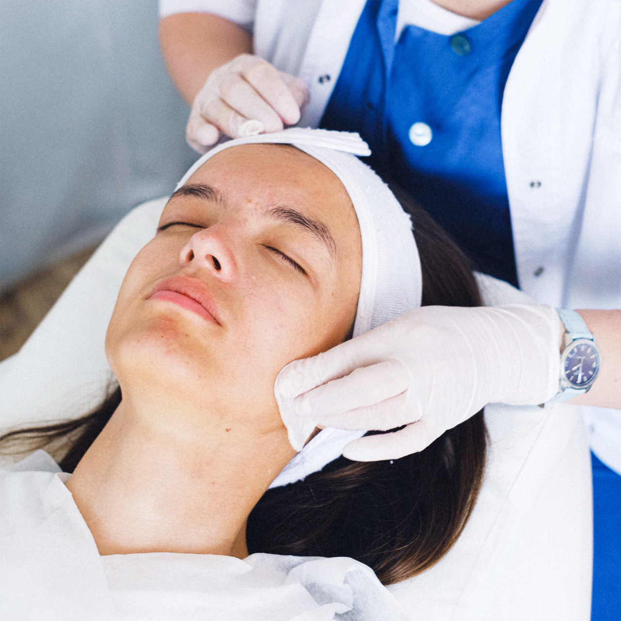 A patient receiving professional facial as gloved provider cleanses skin at dermatology skincare clinic in Birmingham