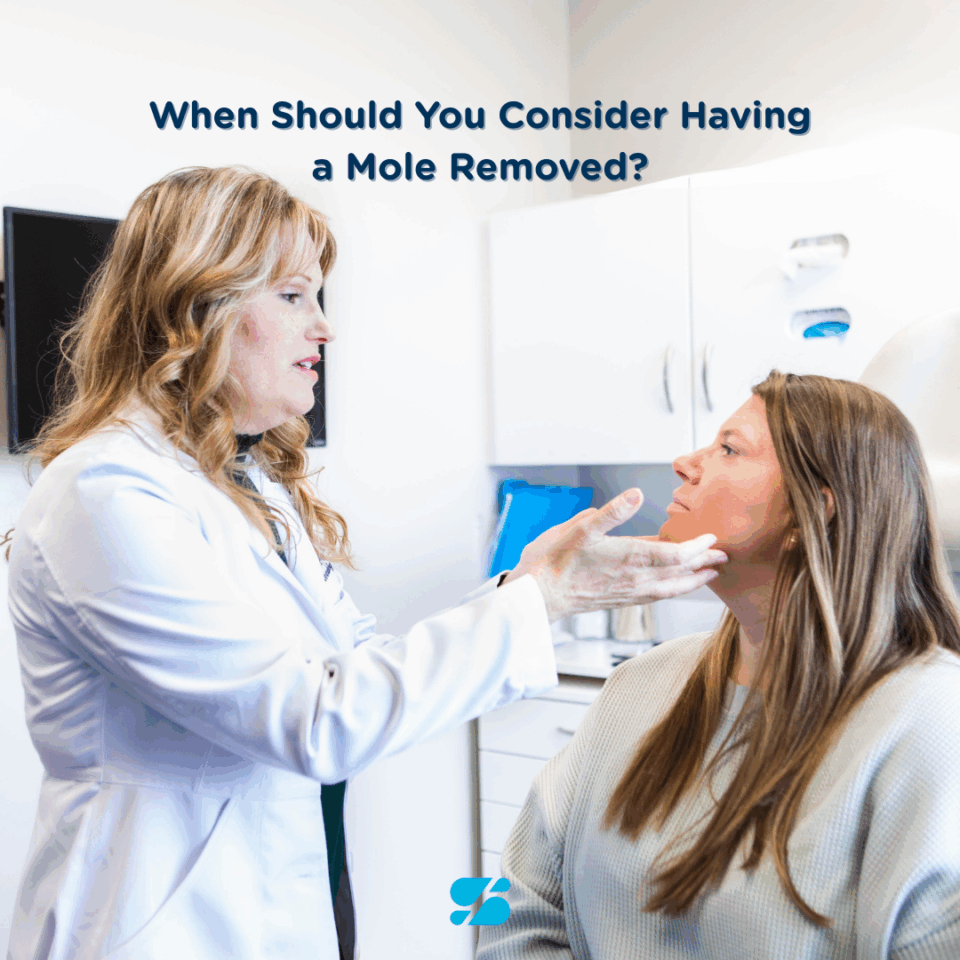 Dermatologist examining patient's face during mole removal consultation in Birmingham, AL dermatology clinic.
