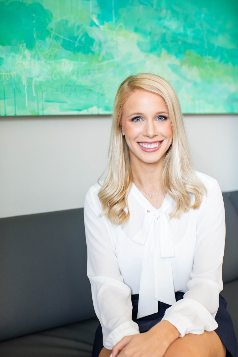 Smiling woman with clear skin in white blouse, professional headshot for Birmingham dermatology and cosmetic skincare clinic