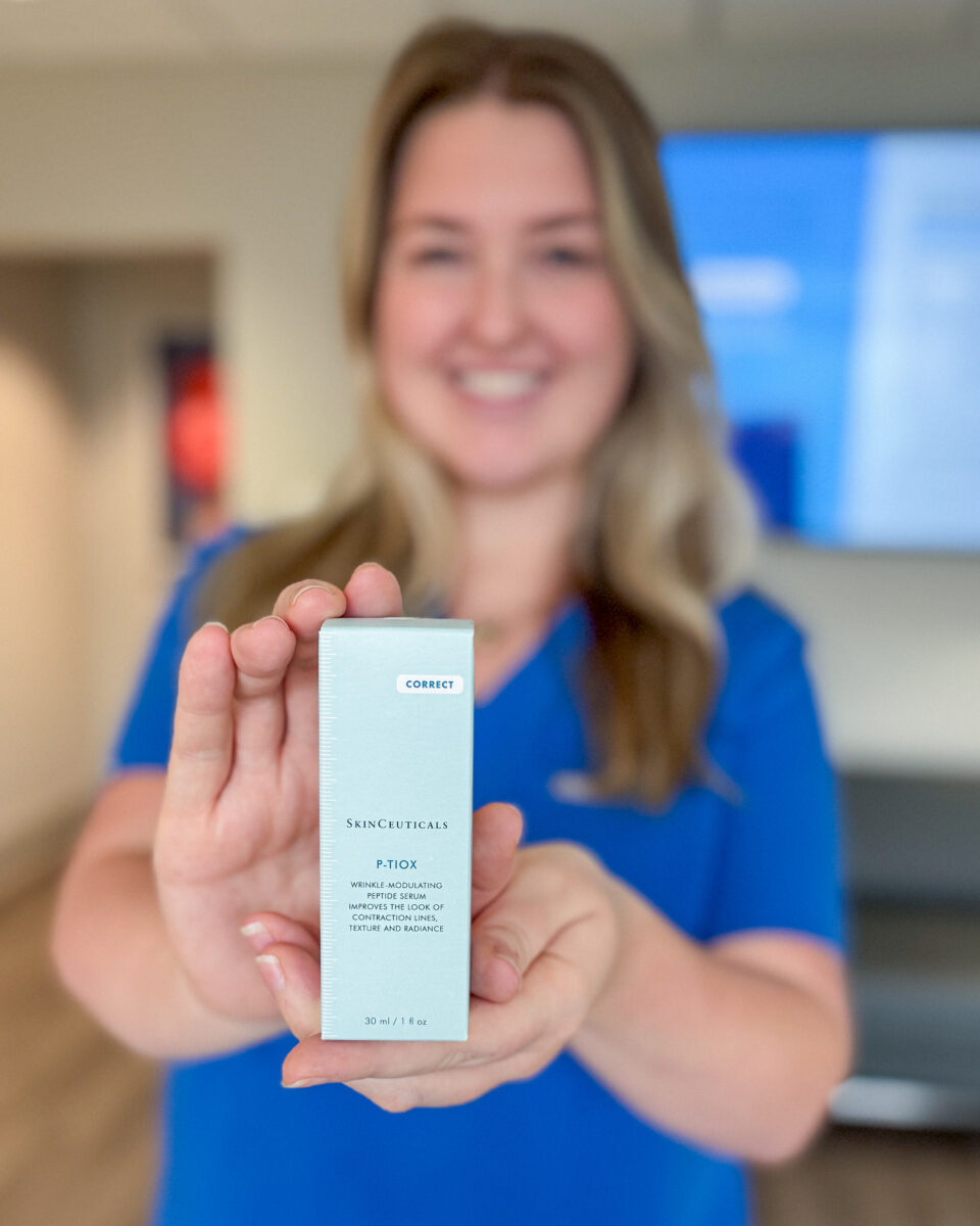 A woman holding a SkinCeuticals P-Tiox wrinkle-modulating peptide serum box toward camera, Birmingham, AL