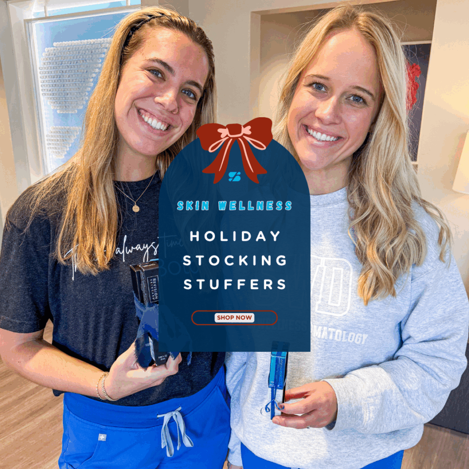 Two smiling women holding skincare products in a dermatology clinic promoting Skin Wellness holiday stocking stuffers