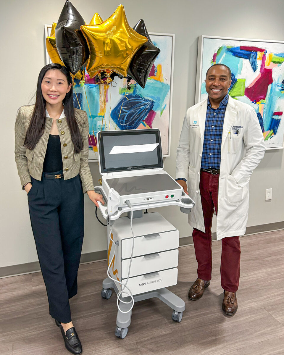 A woman and a doctor beside an aesthetic device and celebratory balloons in a dermatology clinic, Birmingham