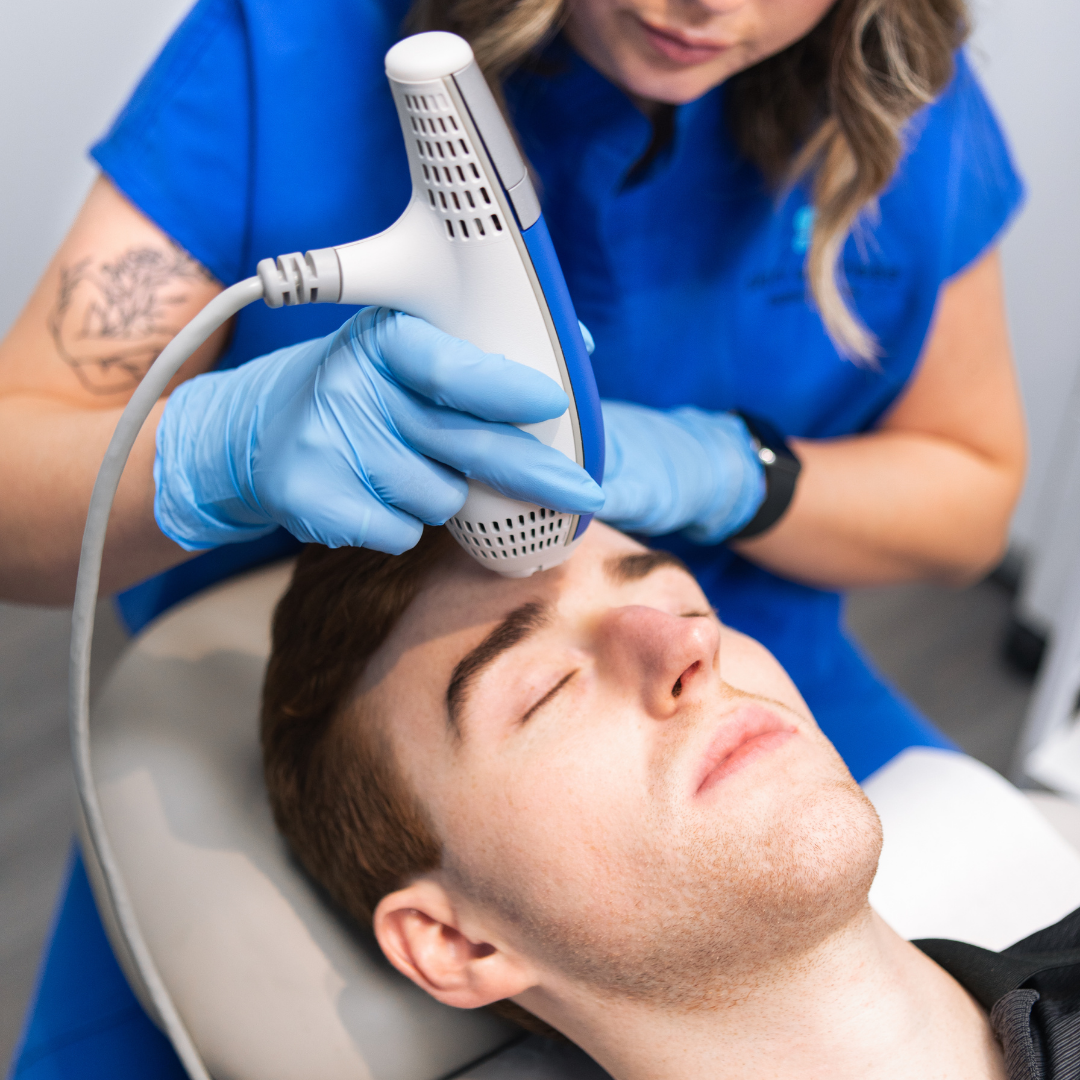 Dermatology clinician using handheld laser on a man's forehead for facial skin treatment.