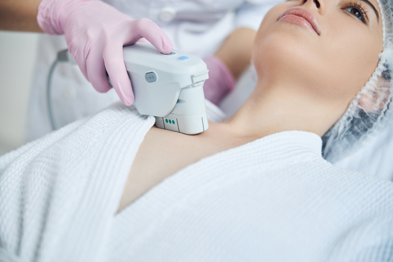 A woman receiving a non-invasive skin-tightening treatment on her décolletage with a handheld device.