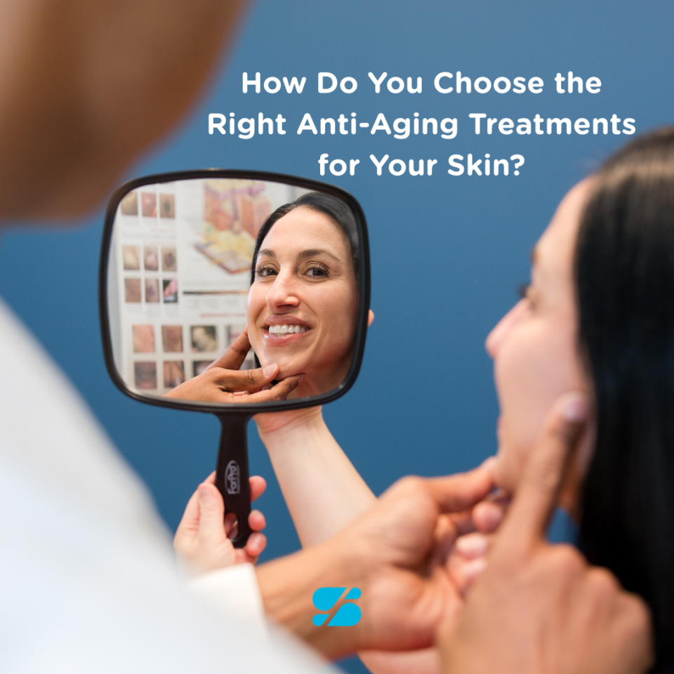 A patient smiling in a hand mirror during a dermatology consultation about anti-aging treatments in Birmingham.