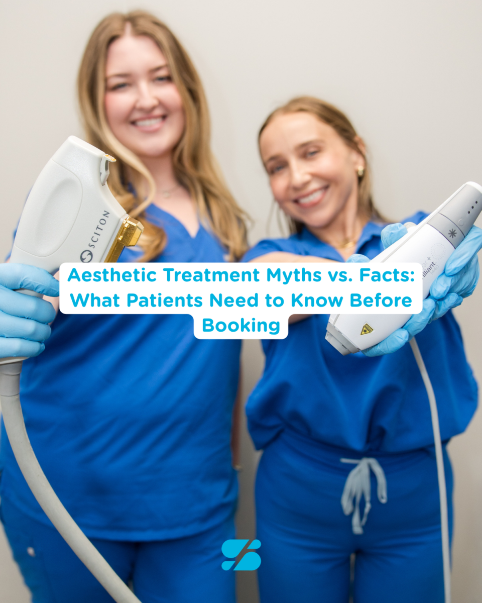 Two women in blue scrubs holding laser devices, smiling at dermatology clinic in Birmingham, AL